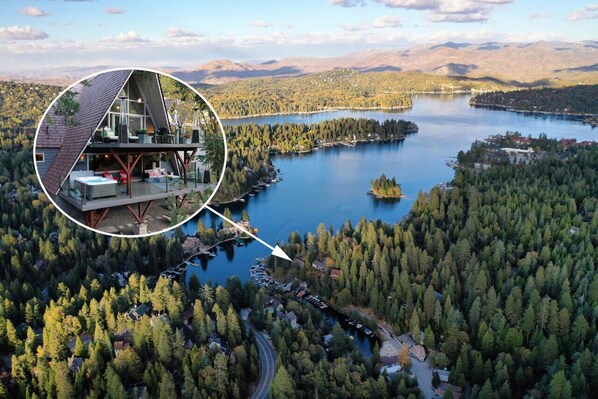 An aerial view of a lakeside property with a prominent house featuring a large deck and a circular inset highlighting a modern interior with a sloped roof.