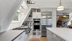 A modern kitchen with stainless steel appliances, white cabinetry, and a built-in oven. - Rocky Point Lakefront | Private Dock & Hot Tub (Lake Arrowhead)