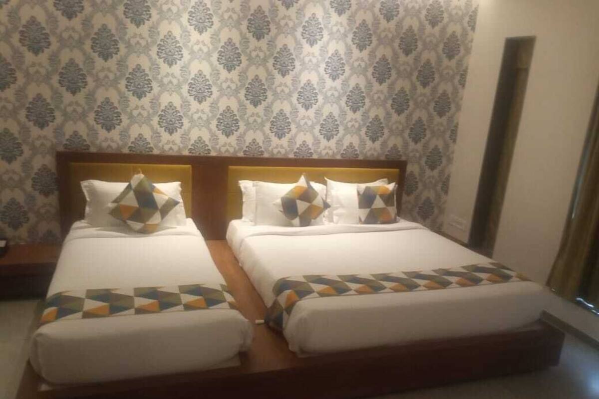 A double bed with patterned pillows and a geometric bedspread in a room with patterned wallpaper.