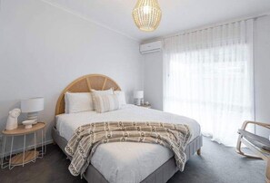 Quarto com cama, mesas de cabeceira, luminária, cadeira e luminária pendente.