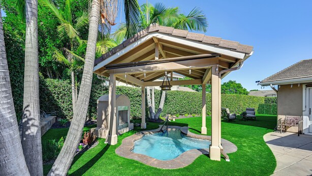 A covered outdoor area with a swimming pool, surrounded by well-maintained grass and palm trees. - 13 Mi to Downtown San Diego: Quiet Home w/ Spa! (Chula Vista)
