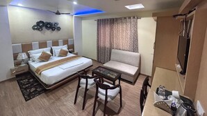Una habitación de hotel con cama, sofá, escritorio con silla y televisor.