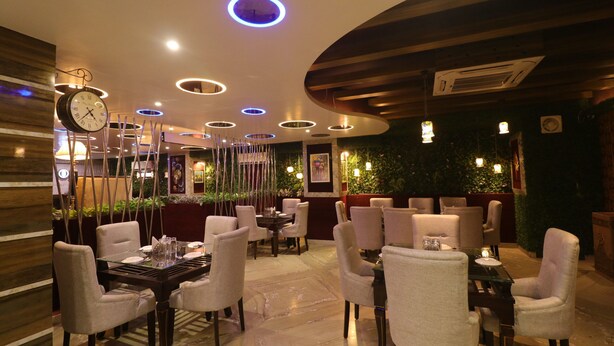 Un restaurante con mesas redondas, sillas y un reloj en la pared.