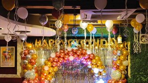 Una habitación decorada con un cartel de 'HAPPY BIRTHDAY', globos y un ambiente festivo.