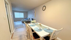 A dining area with a white table, blue placemats, and white chairs.