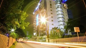 Ένα πολυώροφο ξενοδοχείο με μοντέρνο σχεδιασμό, που διακρίνεται για την εντυπωσιακή γυάλινη πρόσοψή του και τις φωτεινές επιγραφές του.