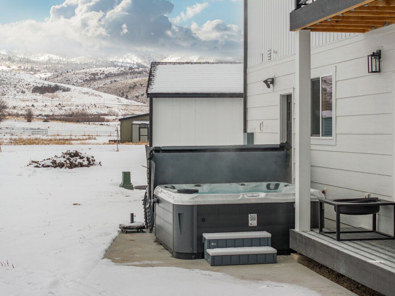 Un jacuzzi junto a una casa con paisaje nevado al fondo.