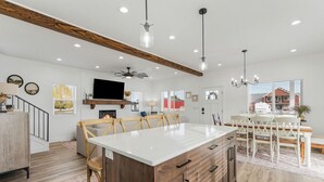 Una cocina amplia con una isla grande, vigas de madera e iluminación colgante.