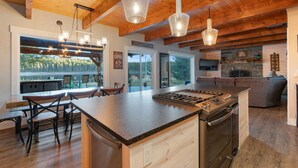 Een moderne keuken met een centraal eiland, houten balken in het plafond en hanglampen.