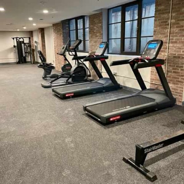 Een sportschool met loopbanden, een hometrainer en krachttoestellen.