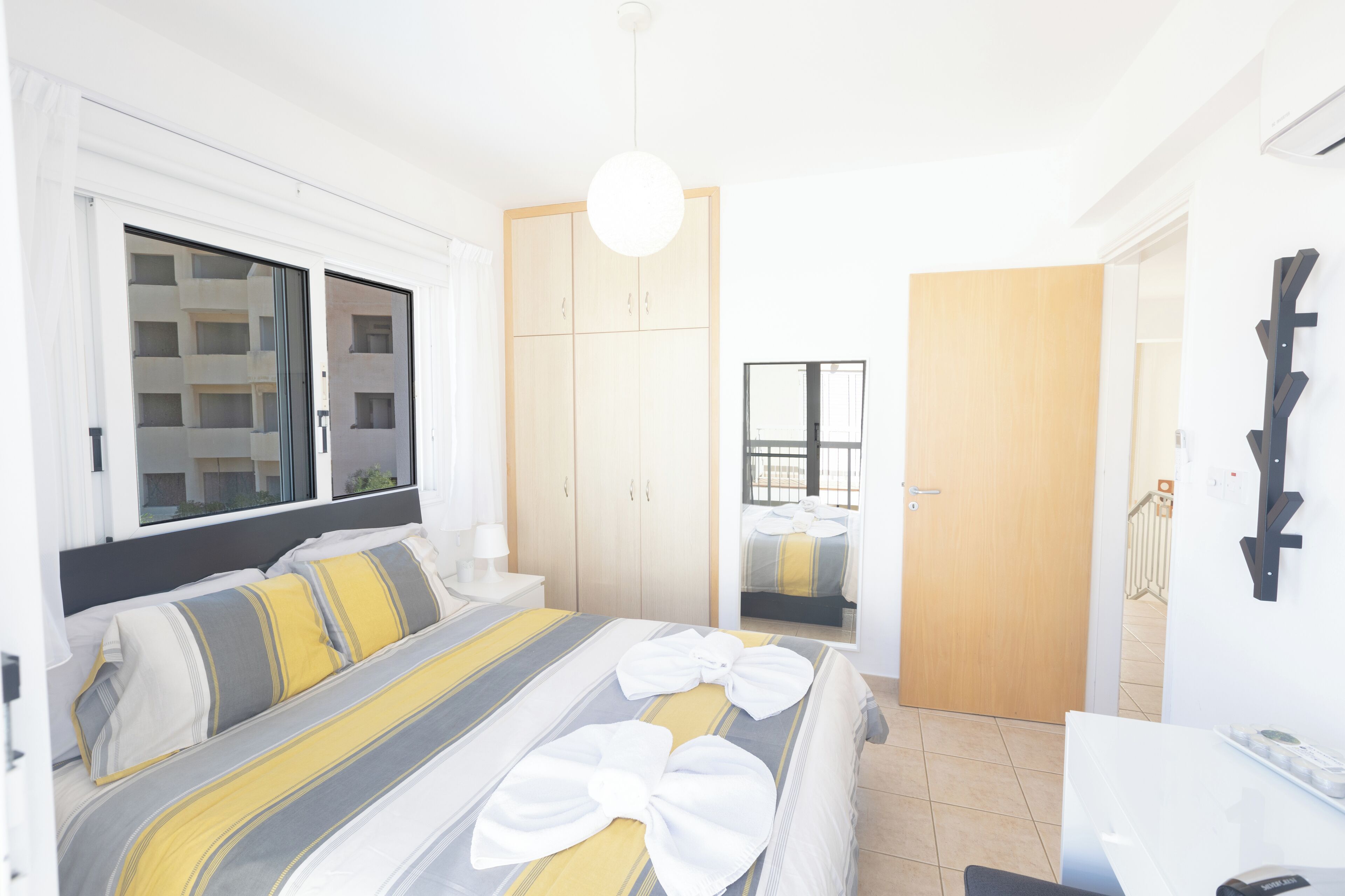 Habitación de hotel moderna con una cama grande, un armario, un baño y vistas al exterior.