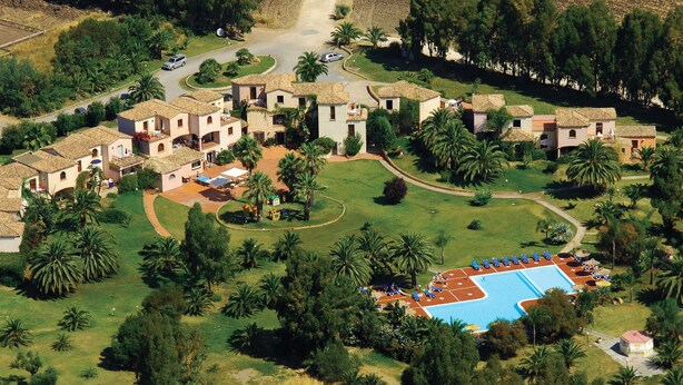 An aerial view of a resort with multiple villas, a swimming pool, and lush greenery.