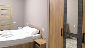 Un dormitorio con cama, armario de madera y mesita de noche.