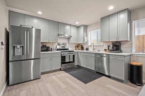 A modern kitchen with stainless steel appliances, grey cabinets, and a black trash bin. - Urban Oasis in the Heart of Sacramento! (Sacramento)