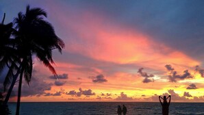 Cena de praia com palmeiras e um pôr do sol.