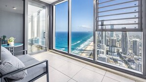 A modern room with a large glass window overlooking a beach and cityscape. - Oceanfront Escape! 2 Beds Home w/ Gym  & Carpark (Surfers Paradise)