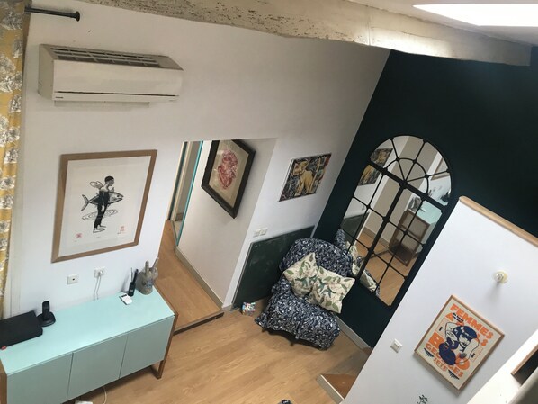 Ein Zimmer mit einem hellblauen Schreibtisch, einer Klimaanlage und Bildern an den Wänden.