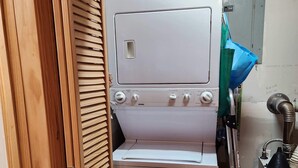 A compact kitchen with a white stove, a sink, and a wooden door.