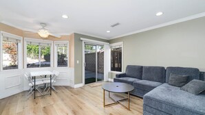 A living room with a grey sofa, a small round table, and a dining table with chairs.