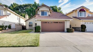 A two-story house with a brown garage door, a small front porch, and a well-maintained lawn.