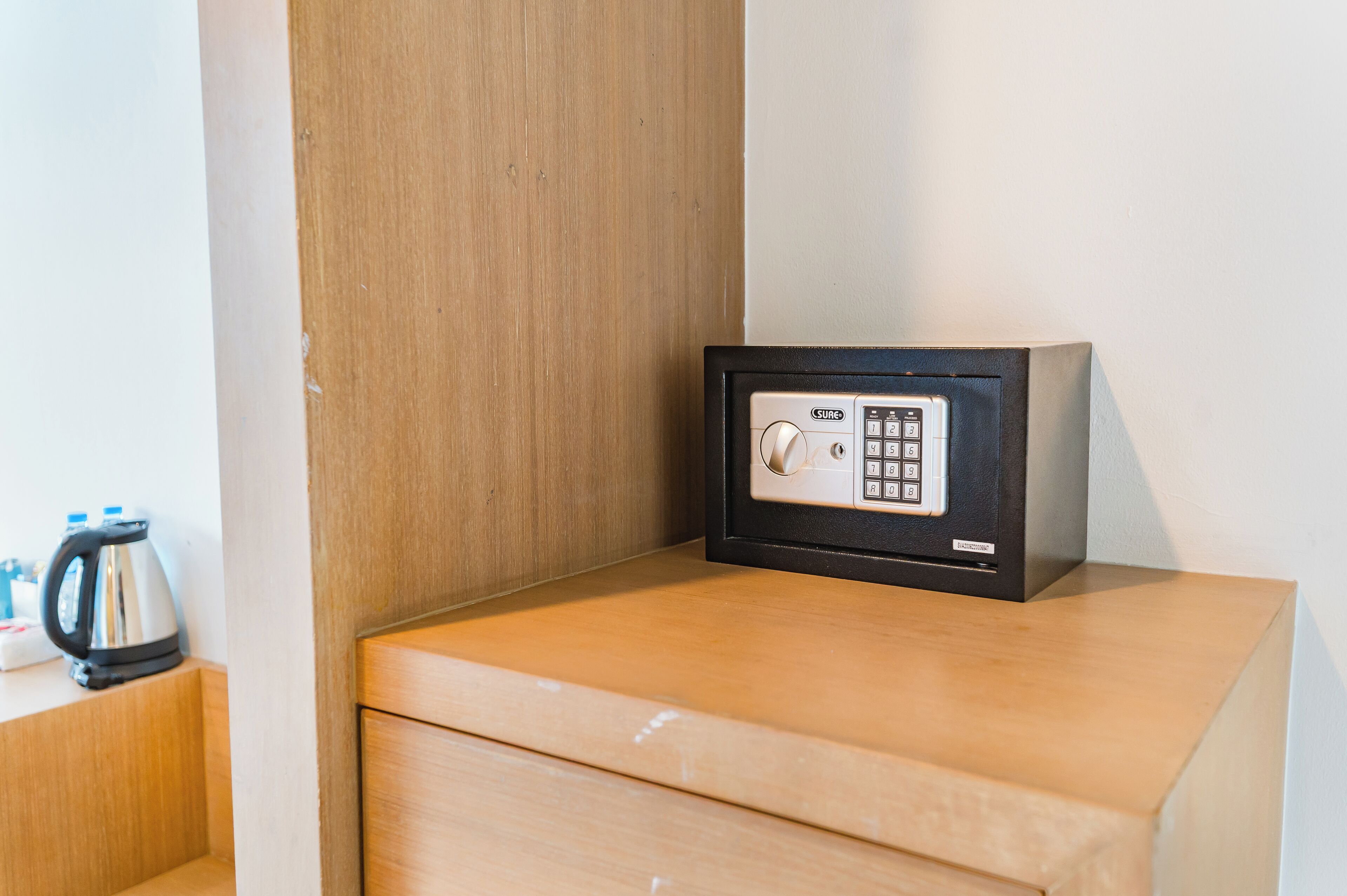 A safe on a wooden counter with a kettle and a box of tissues nearby.