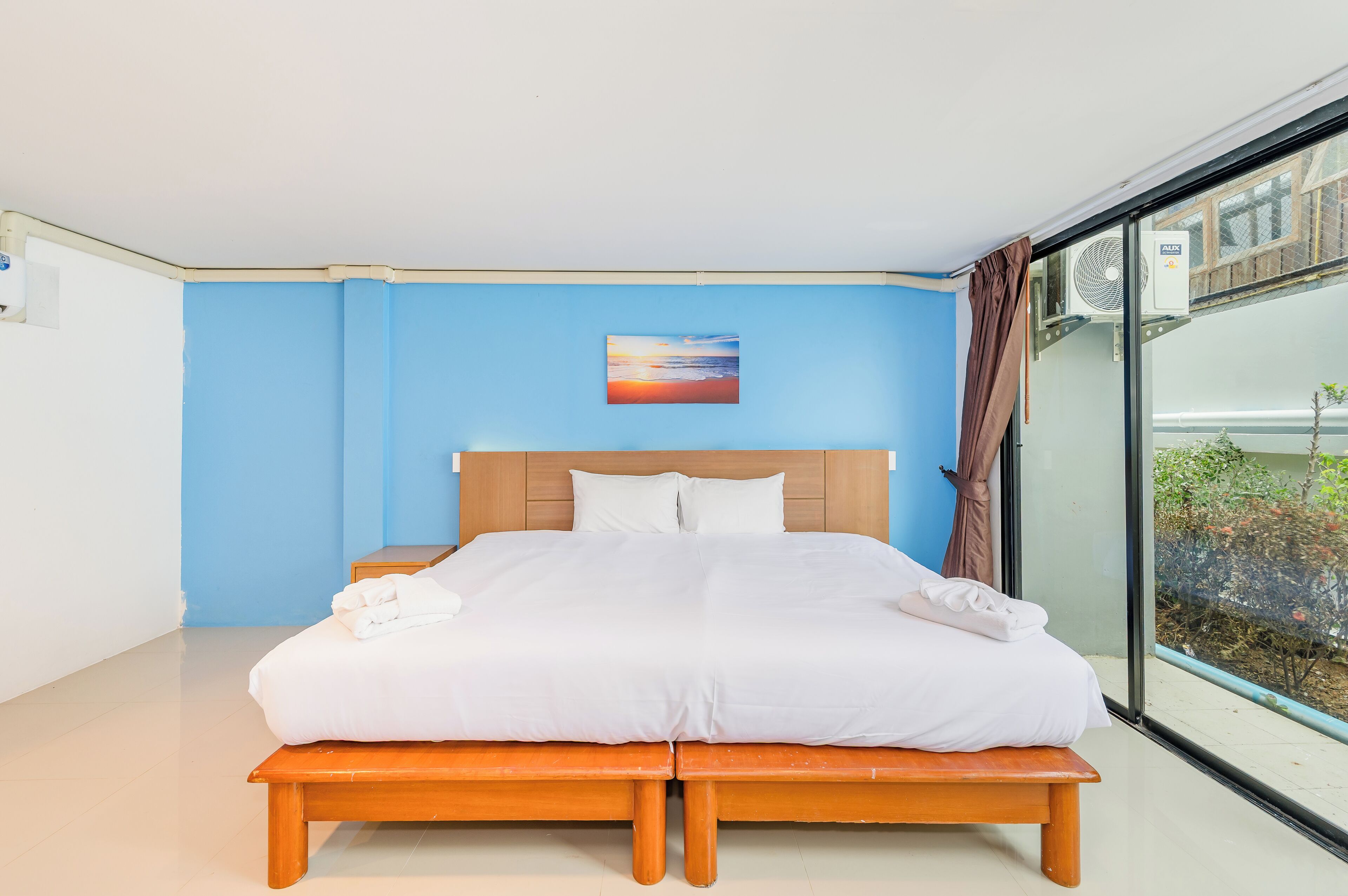 A double bed with white linens, a wooden headboard, and a blue accent wall.