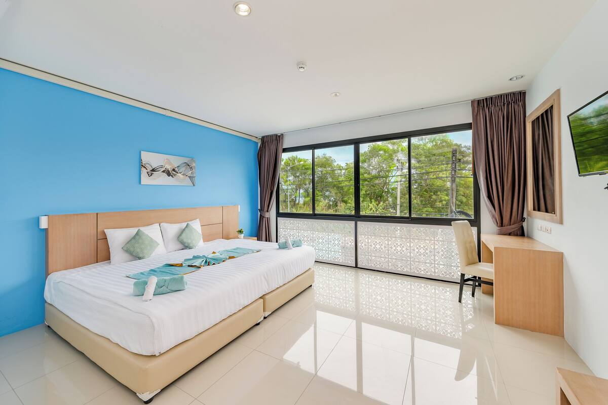 A modern hotel room with a large bed, a desk, and a TV.