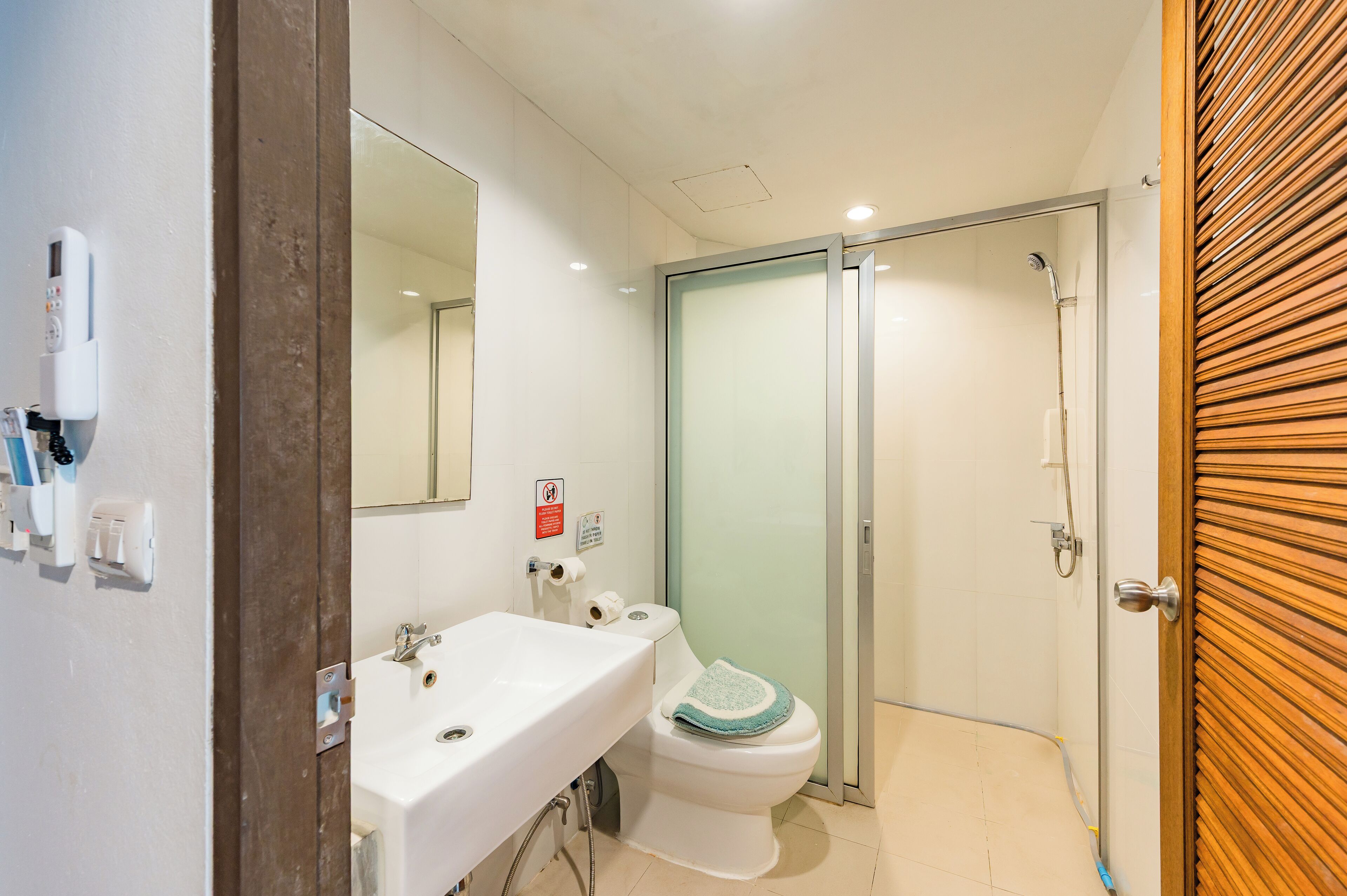 A bathroom with a white sink, mirror, toilet, and glass shower enclosure.