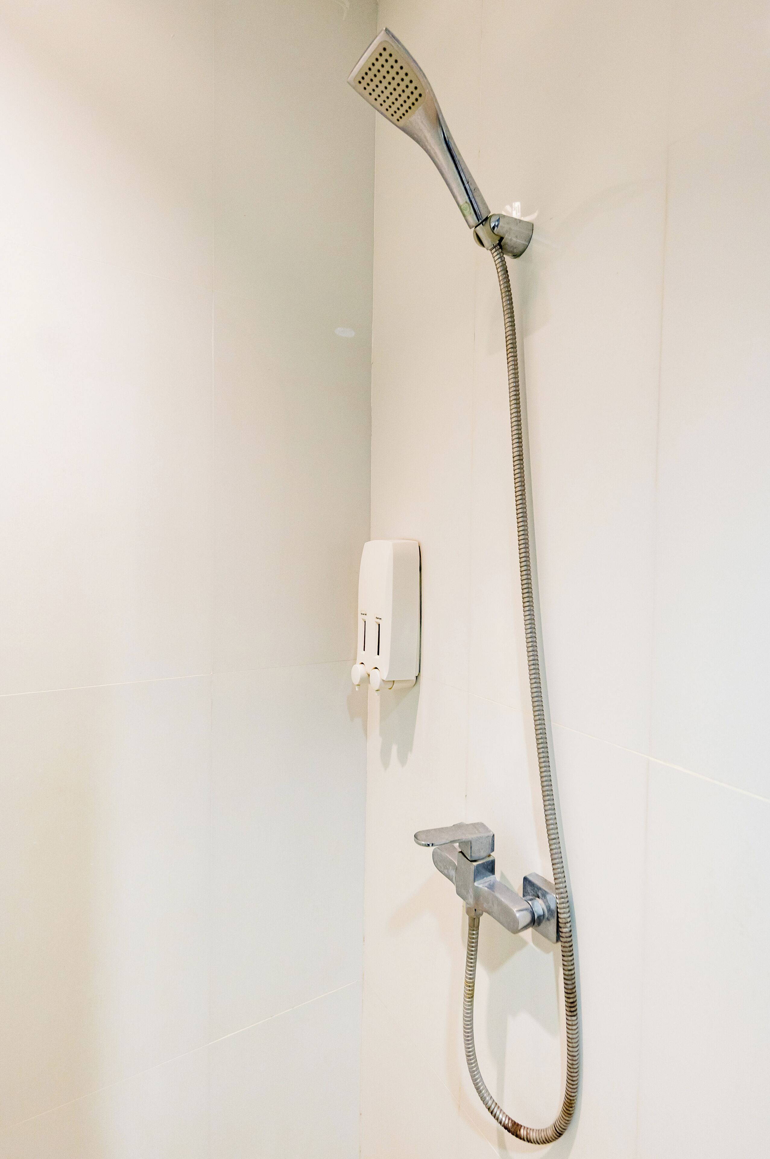 Ducha con cabezal de ducha de mano y panel de control en la pared.