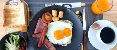 A breakfast plate with toast, bacon, eggs, and a side salad on a table with a placemat.