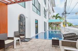 Un'area piscina moderna all'aperto con mobili in vimini e solarium piastrellato.