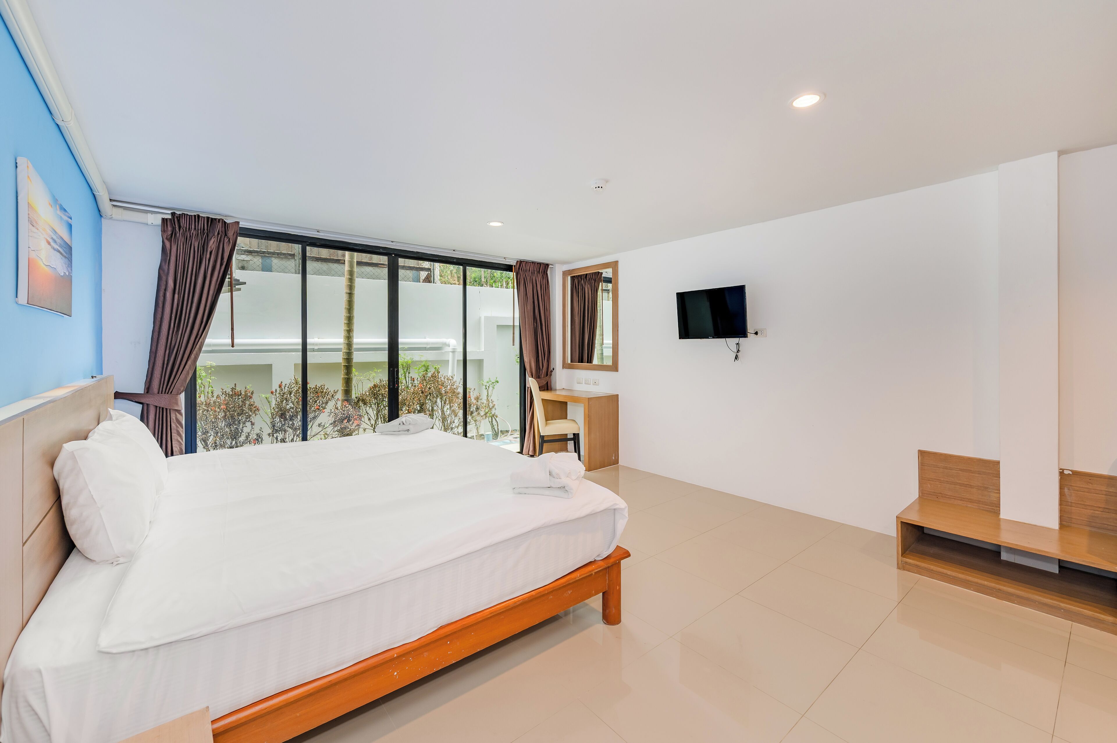 A modern bedroom with a large bed, a desk, and a TV.