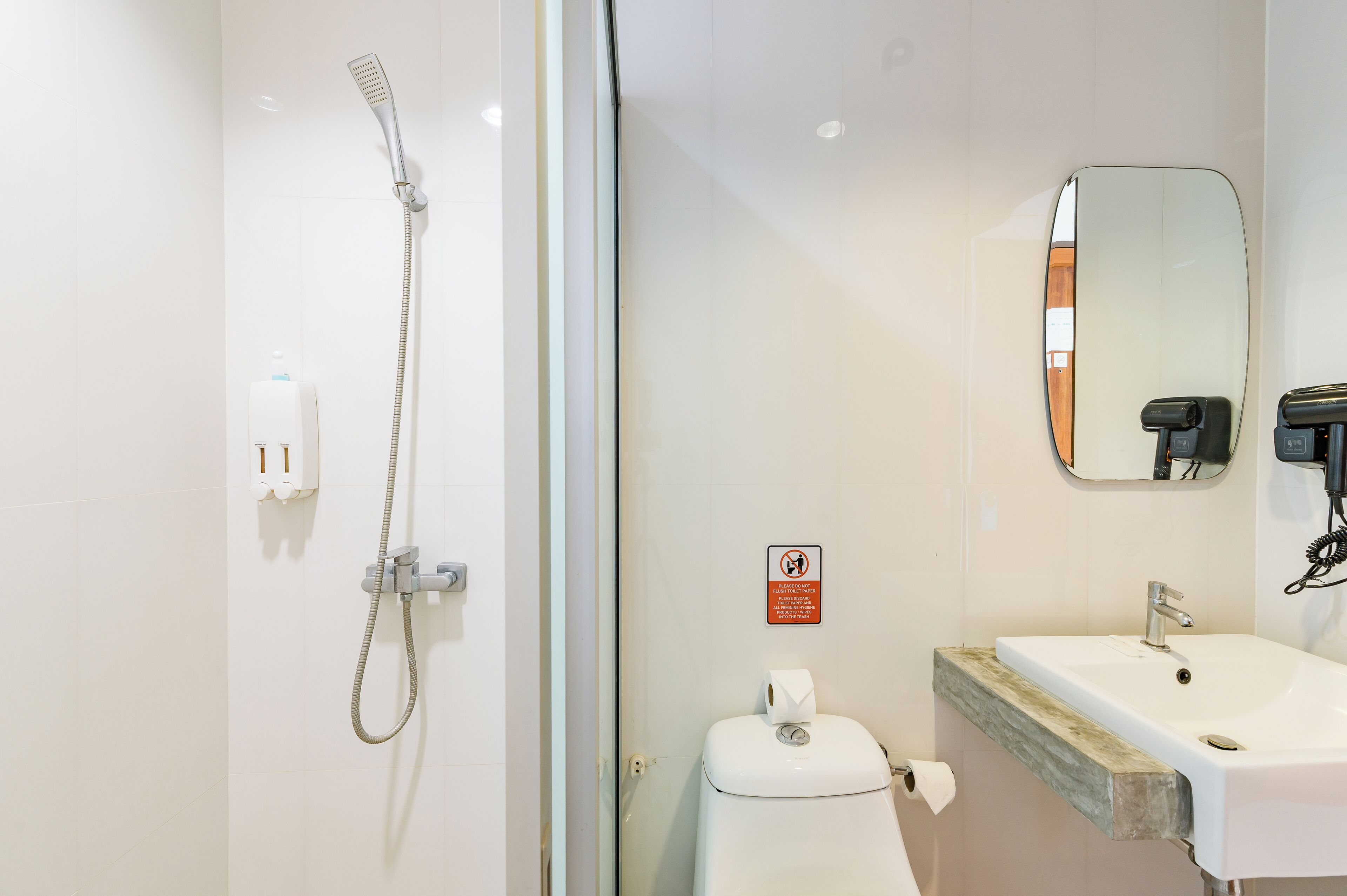 A modern bathroom with a glass shower enclosure, a white sink with a wooden countertop, and a mirror above the sink.