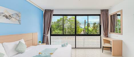 Habitación de hotel moderna con una cama grande, un escritorio y vistas a la vegetación.