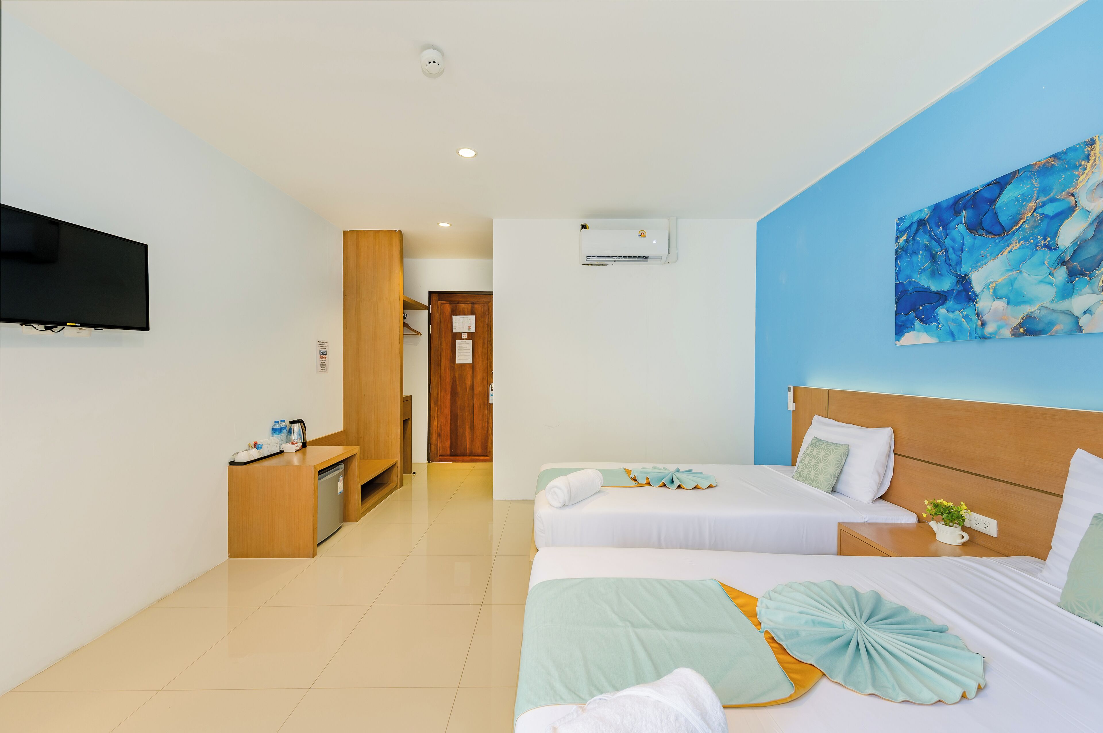 A hotel room with two beds, a TV, a desk, and a bathroom.