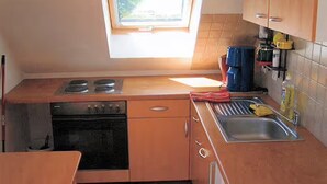 A compact kitchen with a window, a stove, an oven, a sink, and basic amenities. - Apartment 'Ferienwohnung Stadermann' with Private Terrace, Private Garden and Balcony (Walow-Strietfeld)