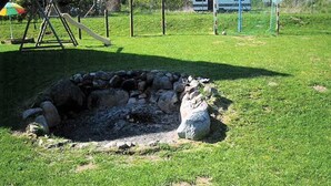 A grassy area with a stone structure, possibly a fire pit, and a swing set in the background. - Apartment 'Ferienwohnung Stadermann' with Private Terrace, Private Garden and Balcony (Walow-Strietfeld)
