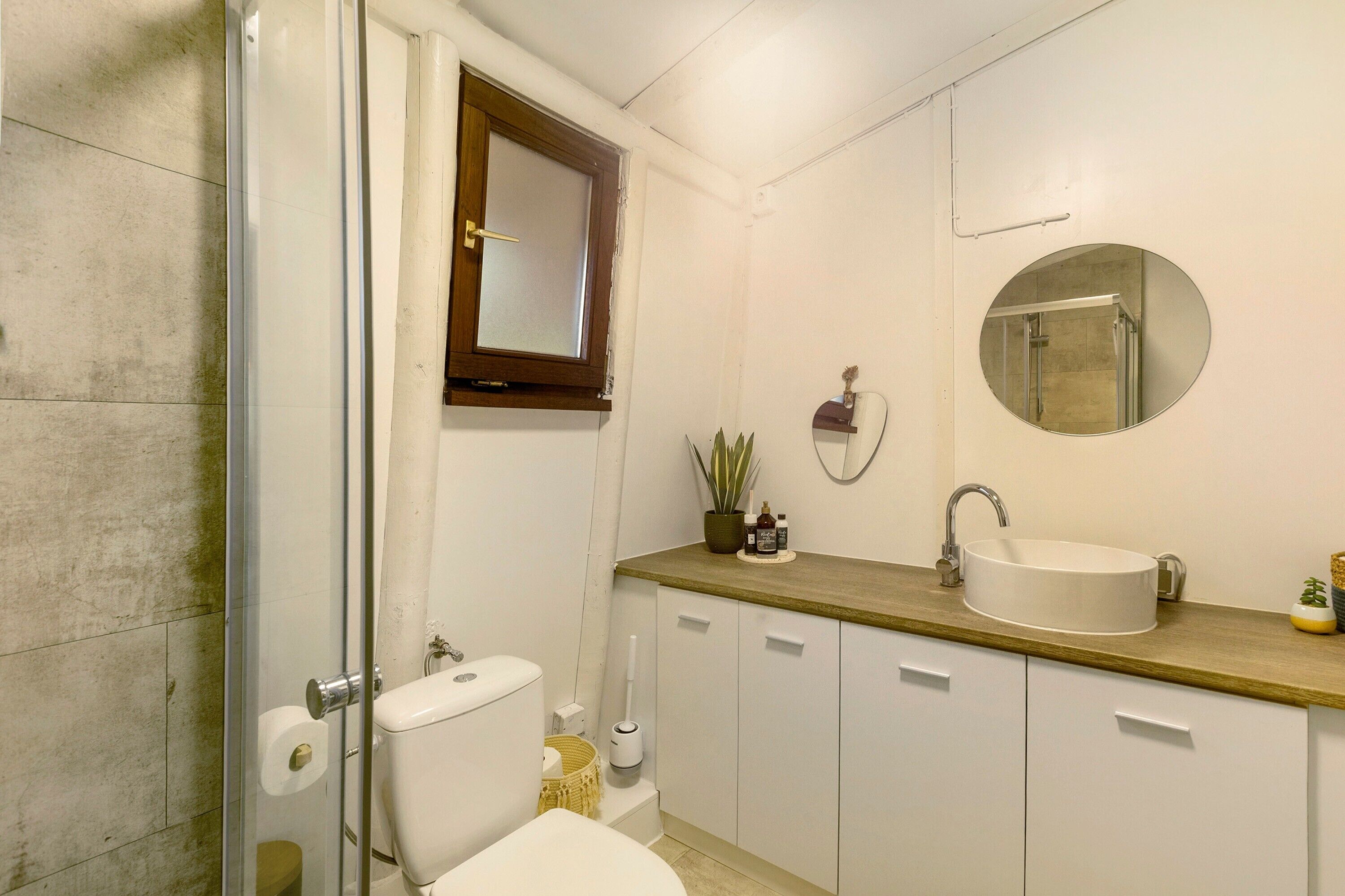 Un baño con inodoro, lavamanos, espejo y ducha.
