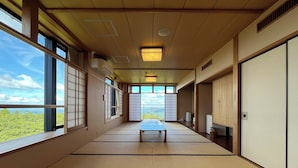 A traditional tatami mat room with a view of greenery and a balcony. - Hikosan Hotel Nagomi (Soeda)