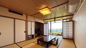 A traditional Japanese room with tatami flooring, a low table, a TV, and sliding doors. - Hikosan Hotel Nagomi (Soeda)