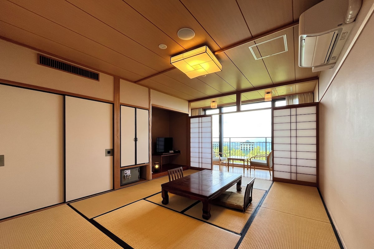 Egy hagyományos japán szoba, tatami szőnyeggel, alacsony asztallal, televízióval és tolóajtókkal.