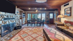 Un interior acogedor con chimenea de piedra, una zona de comedor y un área de descanso confortable con un sofá y una alfombra.