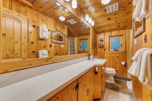 Ein Badezimmer einer Holzhütte mit einem großen Spiegel, einem Waschbecken und einer Toilette.
