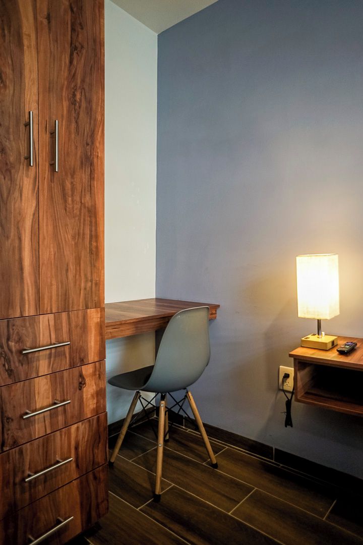 A room with a wooden desk, a chair, a lamp, and a wardrobe.