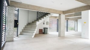 A spacious interior with a concrete staircase, large pillars, and a high ceiling. - 1BR Flat with Smart Access & Parking (San Luis Potosi)