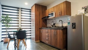 A modern kitchen with wooden cabinets, a built-in microwave, and a refrigerator. - 1BR Flat with Smart Access & Parking (San Luis Potosi)
