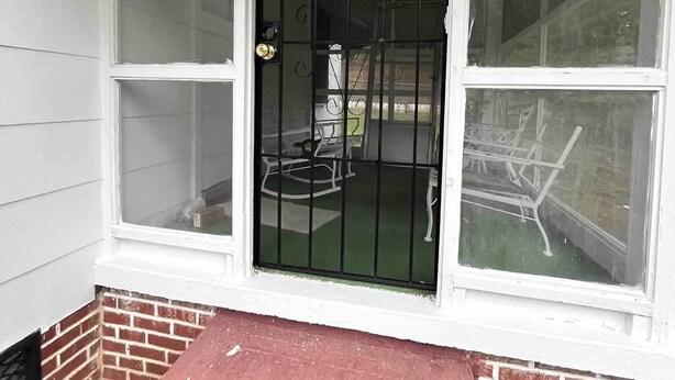 A front door with a black metal gate, a brick foundation, and a small red step leading up to it. - Charming 3-bedroom, spacious home conveniently located near Tuskegee University (Tuskegee)