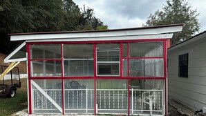 A small, single-story building with a white exterior and red trim. It features large windows and a covered porch area. - Charming 3-bedroom, spacious home conveniently located near Tuskegee University (Tuskegee)