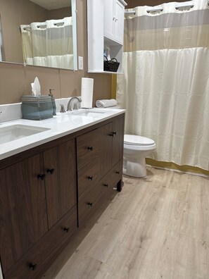 A modern bathroom with a wooden vanity, a white sink, and a toilet. - Charming 3-bedroom, spacious home conveniently located near Tuskegee University (Tuskegee)