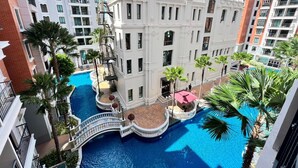 A multi-story hotel with a central pool surrounded by balconies and palm trees.